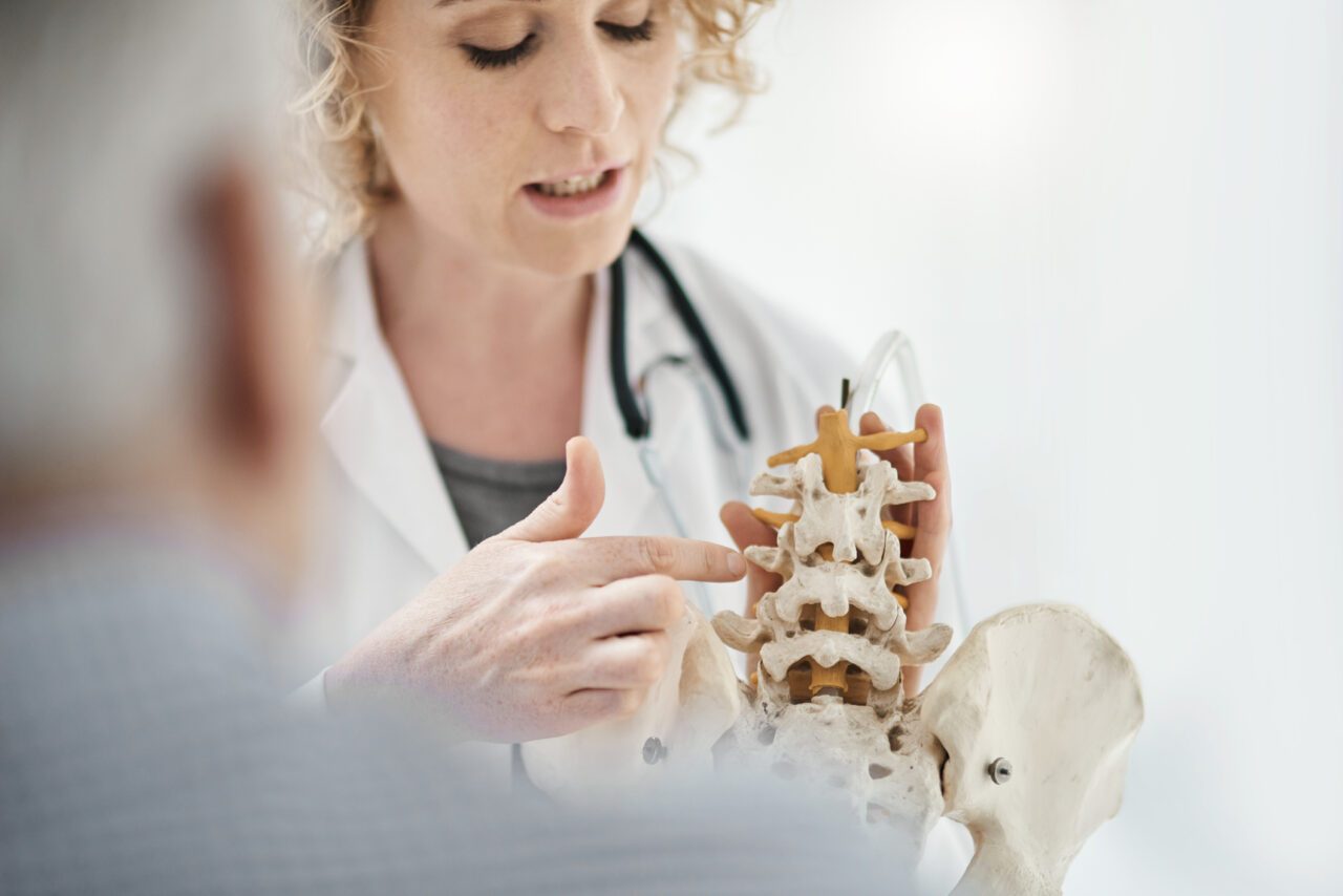 Cropped shot of an attractive young female chiropractor explaining her diagnosis to a male patient using a model skeleton